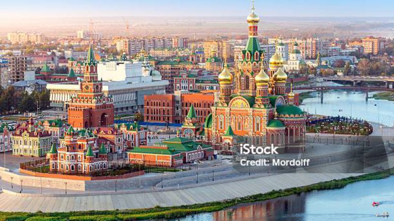 Nice view of the town at sunset. Orthodox church surrounded by beautiful red brick buildings on the city's waterfront. Volga region of Russia, the city of Yoshkar-Ola